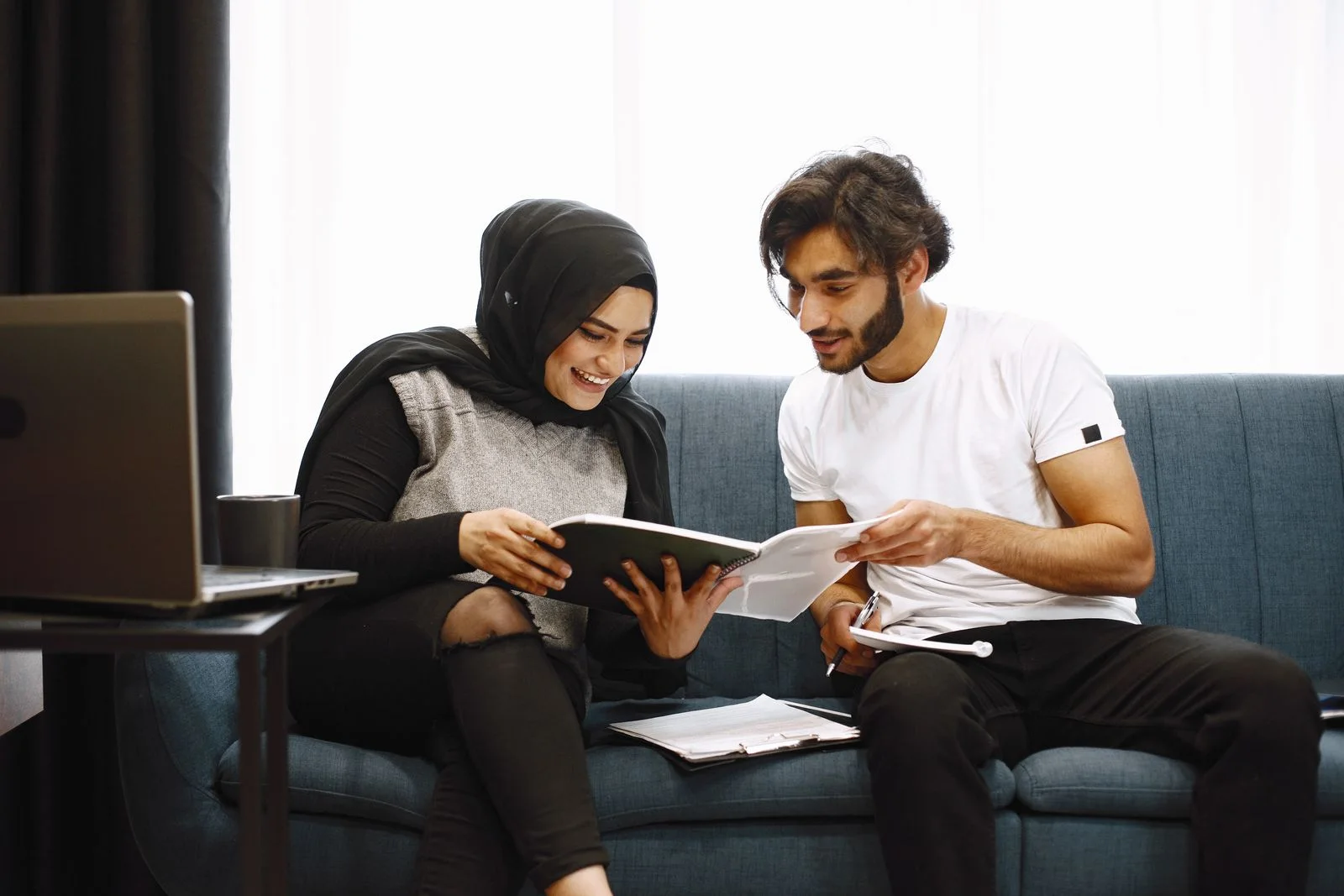 Two people reading paperwork together on a sofa